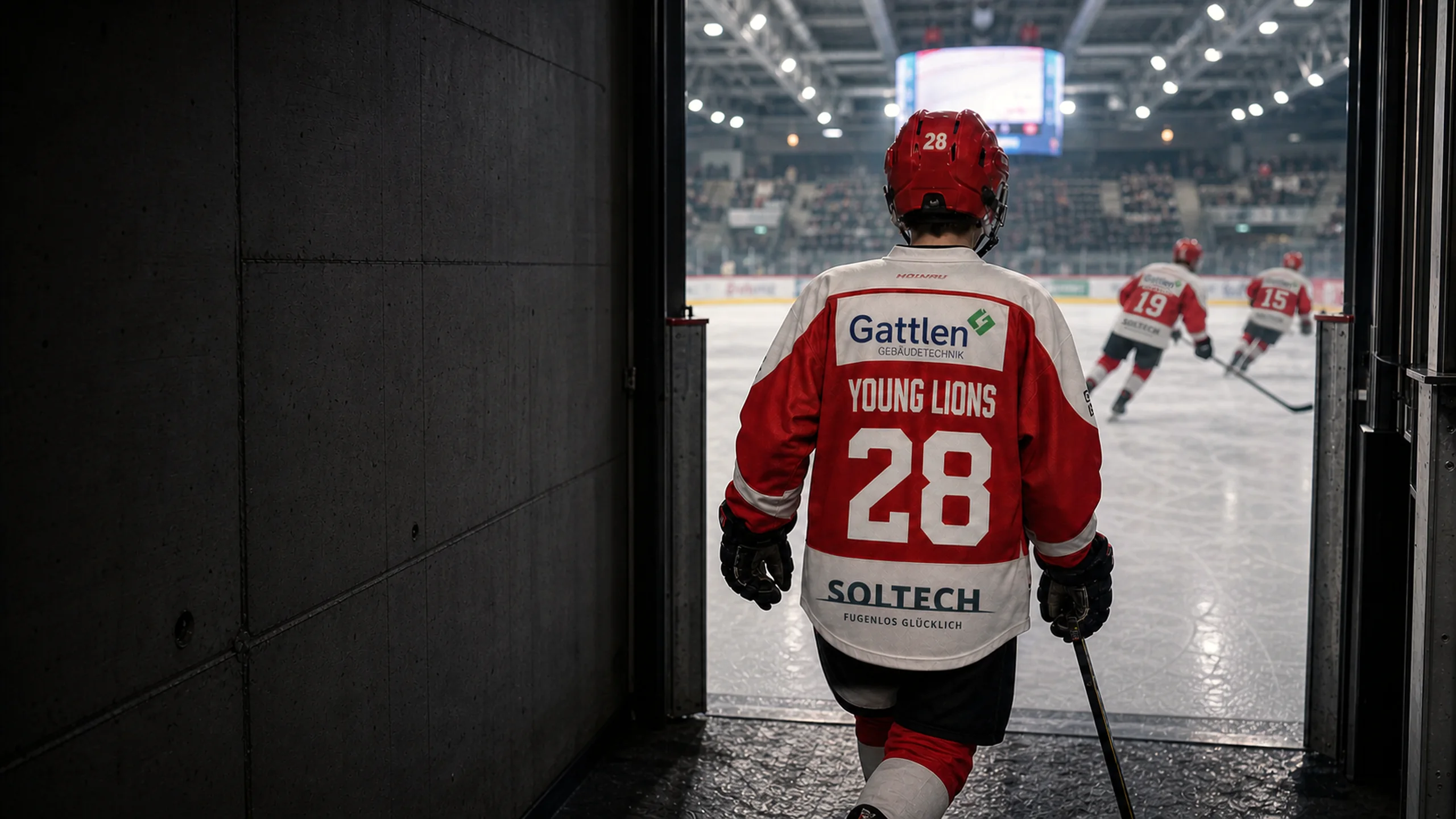 Spieler der Young Lions betritt durch den Halleneingang das Eis, während Teamkollegen bereits Schlittschuh laufen